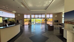 A spacious lobby with a reception desk, seating area, and large windows offering views of the outdoors.