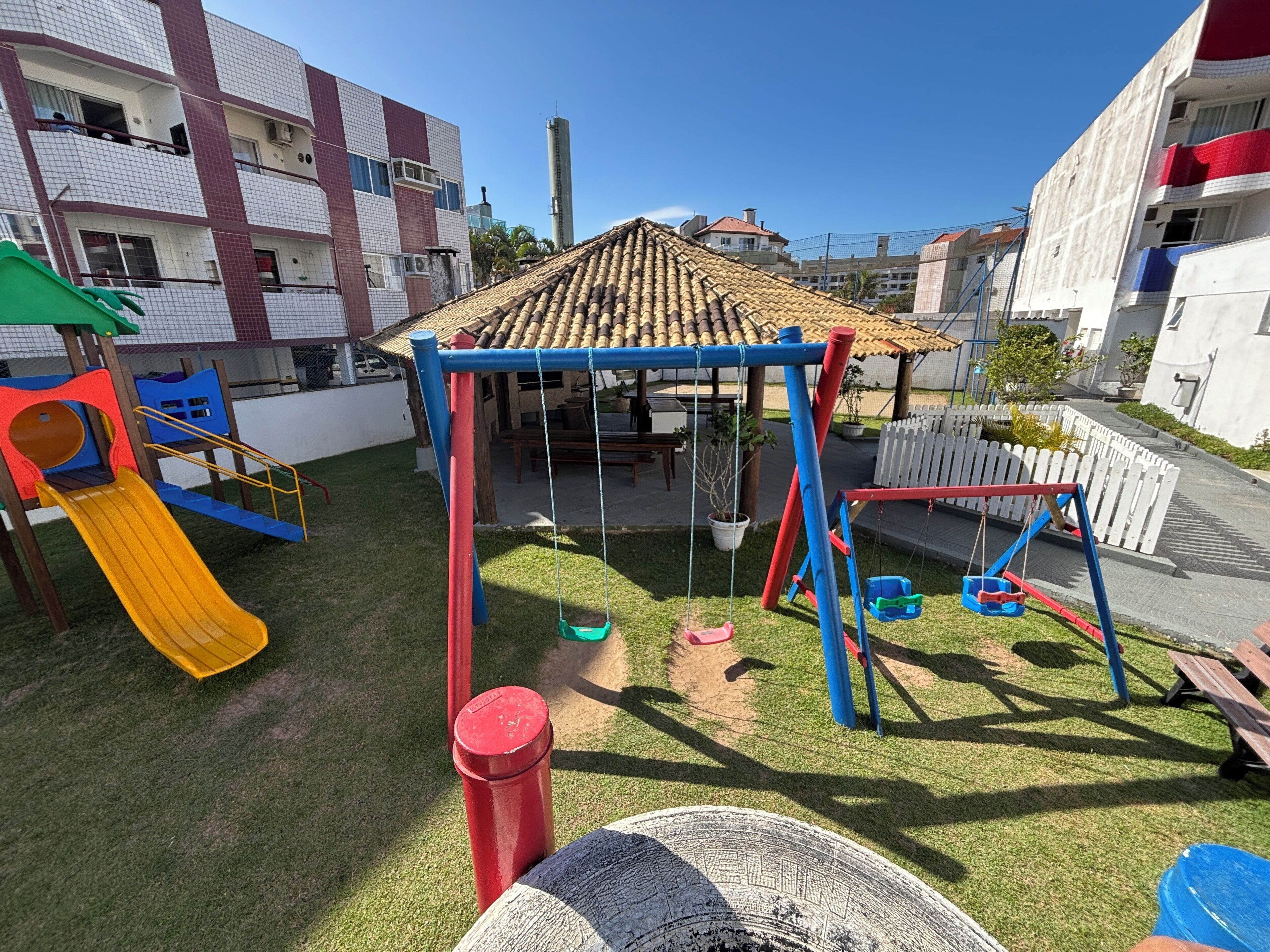 Um parquinho com escorrega, balanços e uma estrutura de escalada.