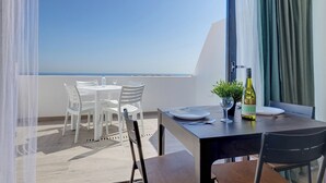 A balcony with a table set for two, a bottle of wine, and a glass of water. - Super Seaview Penthouse, Sliema Creek Guesthouse (Sliema)