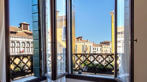 Een raam met uitzicht op historische gebouwen en een balkon met een hekwerk.