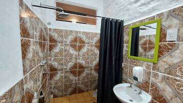 A bathroom with a shower, a sink, and a mirror.
