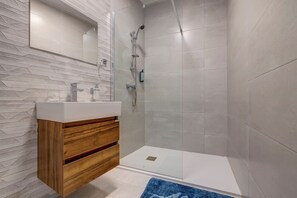 Ein modernes Badezimmer mit Duschkabine aus Glas, Waschtisch aus Holz und großem Spiegel.