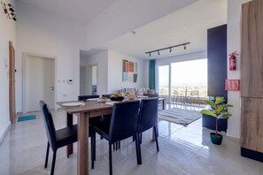 Ein moderner Essbereich mit einem Holztisch, schwarzen Stühlen und Blick auf die Stadt durch große Fenster.