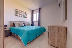 Ein Schlafzimmer mit einem Bett, einem Nachttisch, einem Holzschrank, einer Wandklimaanlage und einem Fenster mit Vorhängen.