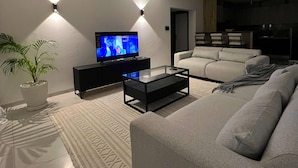 Una sala de estar moderna con un televisor de pantalla plana, un sofá, una mesa de centro y una planta en maceta.