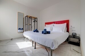 A hotel room with a bed, a nightstand, a mirror, and a wardrobe.