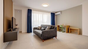 A modern living room with a grey sofa, a flat-screen TV, and a wooden sideboard.
