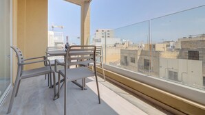 Un balcón con mesa y sillas, con vista a un paisaje urbano.
