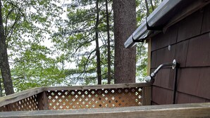Une terrasse en bois avec une clôture à treillis, une main courante en métal et une porte en bois dotée d’une poignée en métal.