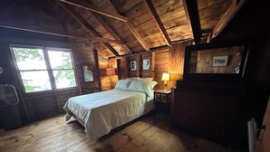 Une chambre dans une cabane en bois, avec un lit, des lampes de chevet et une fenêtre.