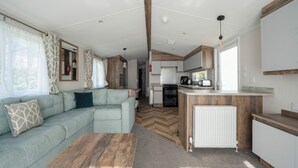 En kompakt autocamper indretning med et tekøkken, en sofa og et spiseområde.