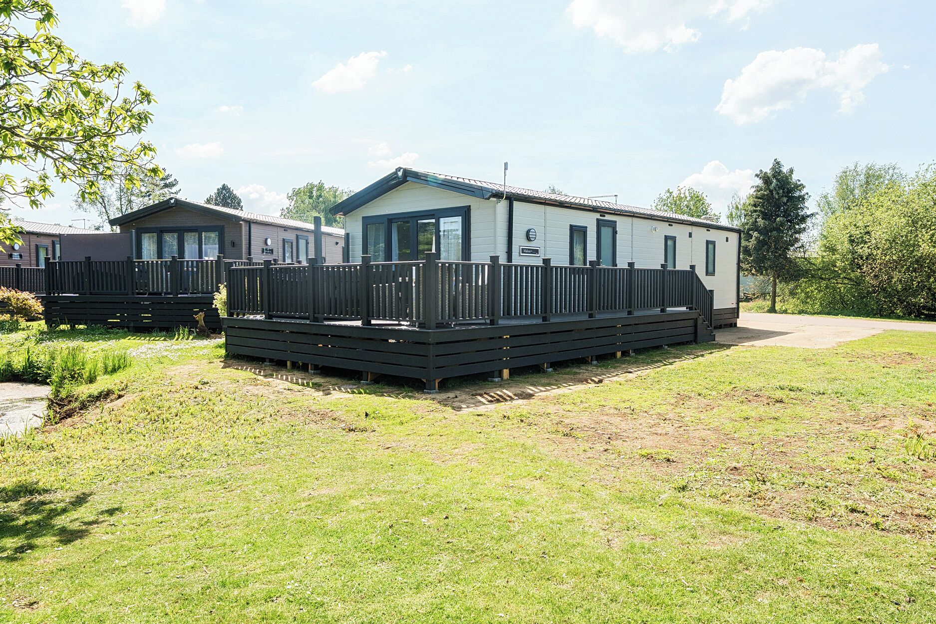 A mobile home with a fenced deck and a small porch.