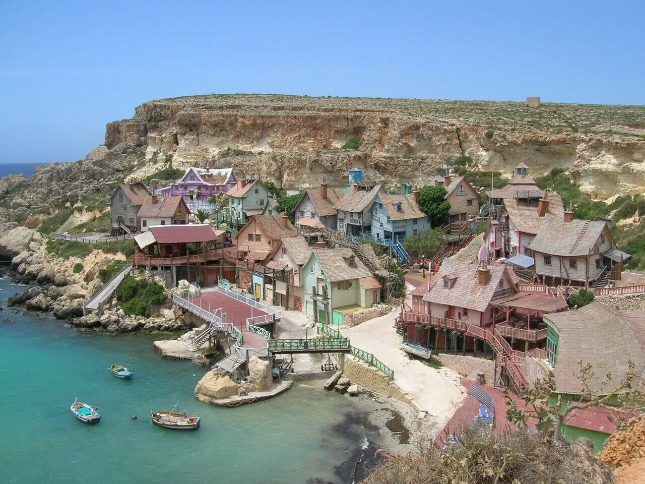Un pueblo costero con casas tradicionales, un puente y barcos.