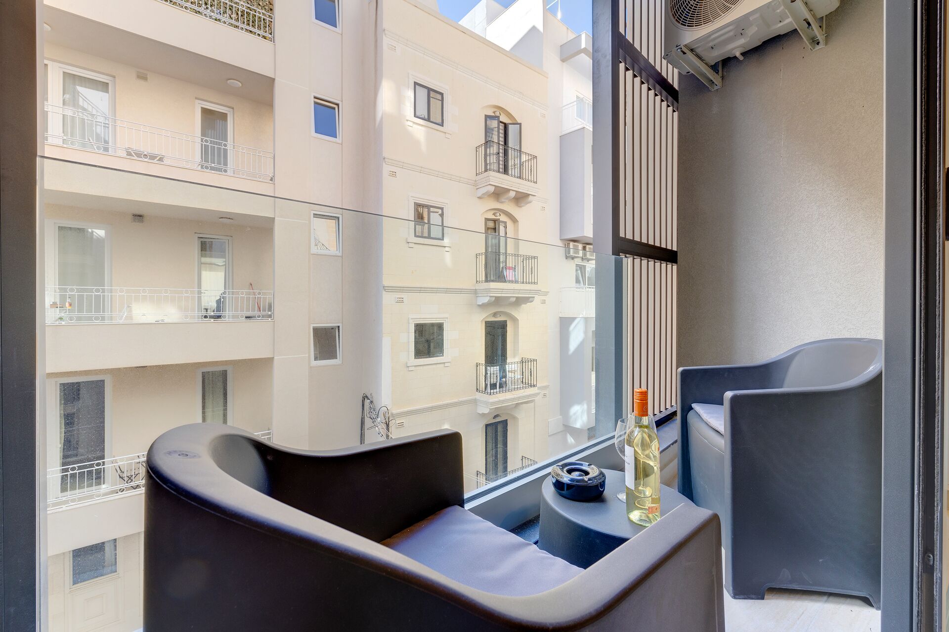 A balcony with a seating area, a bottle of wine, and a glass.