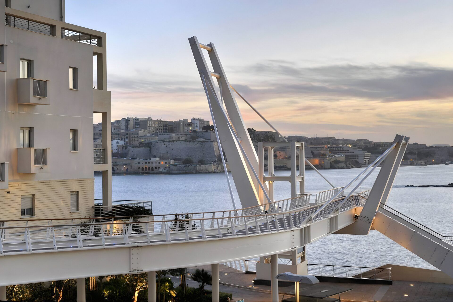 A modern bridge with a pedestrian walkway and a view of a cityscape and water.