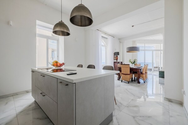 A modern kitchen with a central island, pendant lighting, and a dining area with a view. - Bright 3BR with Sea Views in Central Sliema (Sliema)