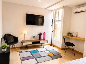 A modern living room with a flat-screen TV, a desk with a lamp, a cactus, and a bicycle-shaped decoration. - Medellin, Bring your toothbrush, in Laureles (Medellín)