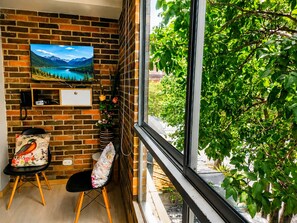 A room with a brick wall, a large window, a desk, a chair, and a painting. - Medellin, Bring your toothbrush, in Laureles (Medellín)