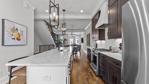 A modern kitchen with a central island, stainless steel appliances, and a staircase leading to another level.