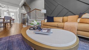 A modern living room with a round coffee table, a sofa, and a staircase.
