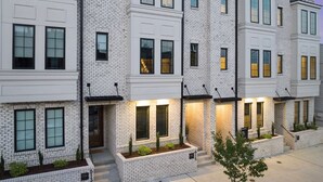 A row of modern townhouses with white brick exteriors, large windows, and small front gardens.