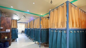 A row of individual changing rooms with curtains, a tiled floor, and a ceiling with recessed lighting. - Laxmi Dormitory | 2 mins walk from Prem Mandir (Vrindavan)