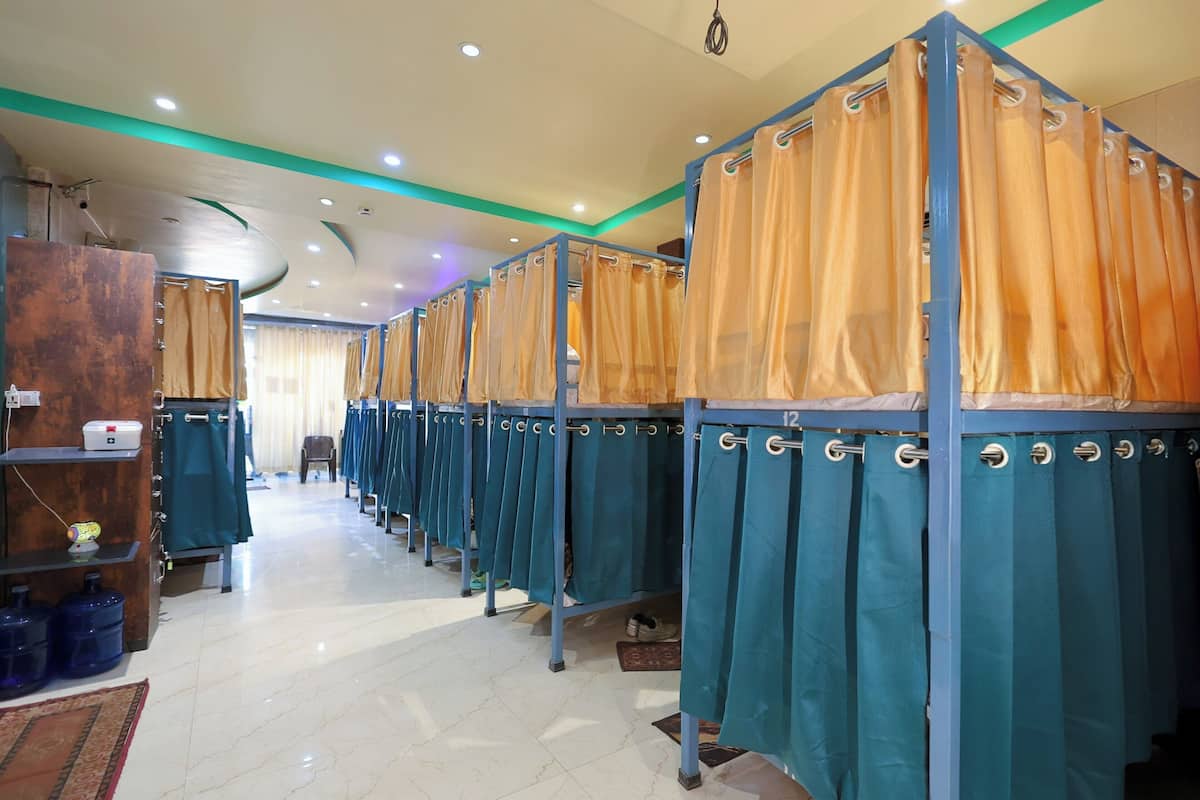 A row of individual changing rooms with curtains, a tiled floor, and a ceiling with recessed lighting.