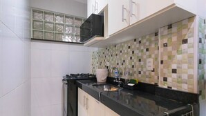 A compact kitchen with white cabinets, a black countertop, and a tiled backsplash. - SUH Copacabana 97 Metro Near Ipanema (Rio de Janeiro)