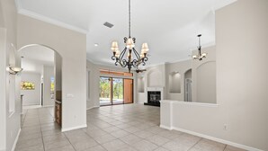 A spacious interior with a high ceiling, a chandelier, and a fireplace. - Sun, Sand & Space: Your Bradenton Vacation Home with Private Pool (Bradenton)