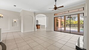 A spacious interior with a large open area, a ceiling fan, and a view through glass doors to an outdoor area. - Sun, Sand & Space: Your Bradenton Vacation Home with Private Pool (Bradenton)