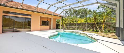 A modern house with a swimming pool, large glass windows, and a covered patio area.