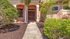 A house with a front entrance, a pathway leading to the door, and surrounding greenery. - Sun, Sand & Space: Your Bradenton Vacation Home with Private Pool (Bradenton)
