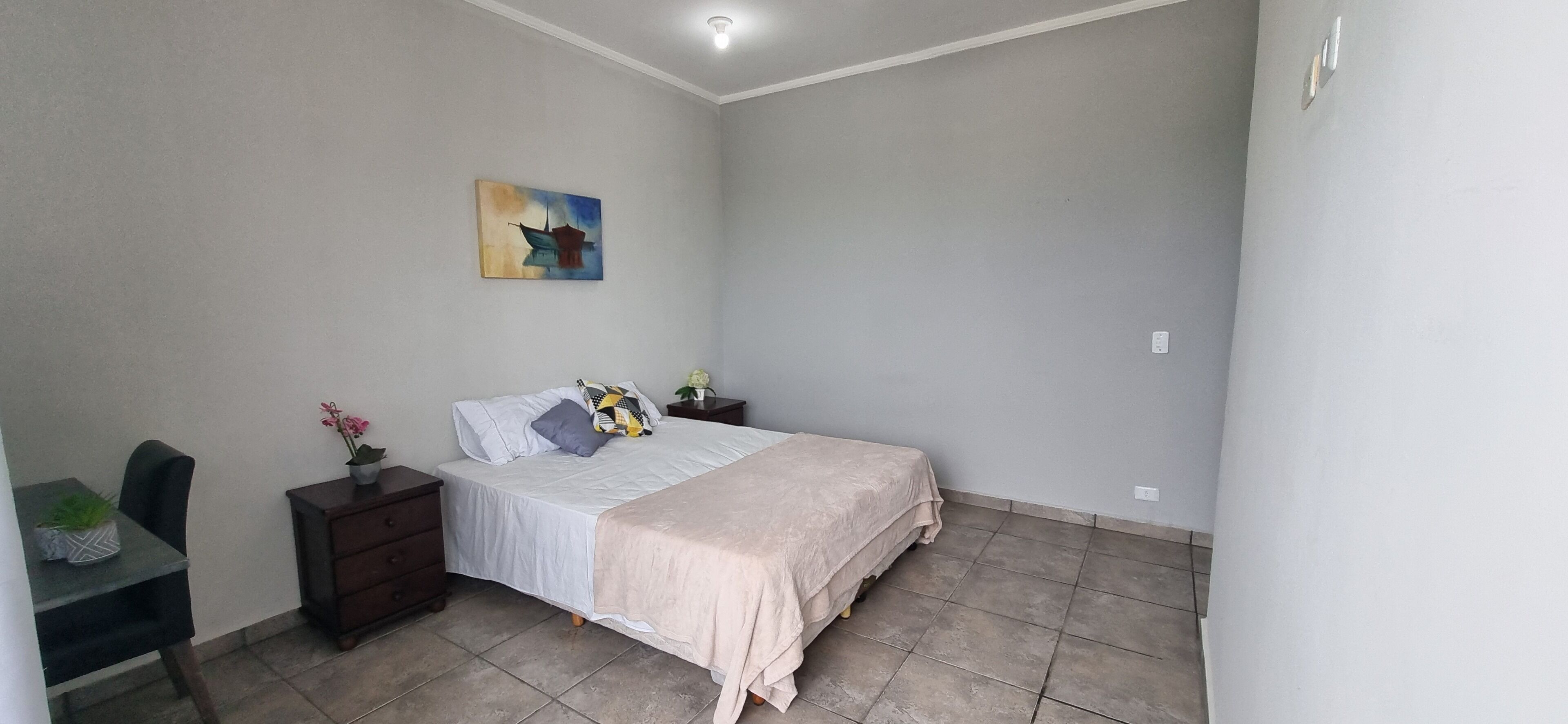 A bedroom with a bed, bedside tables, a desk, and a chair.