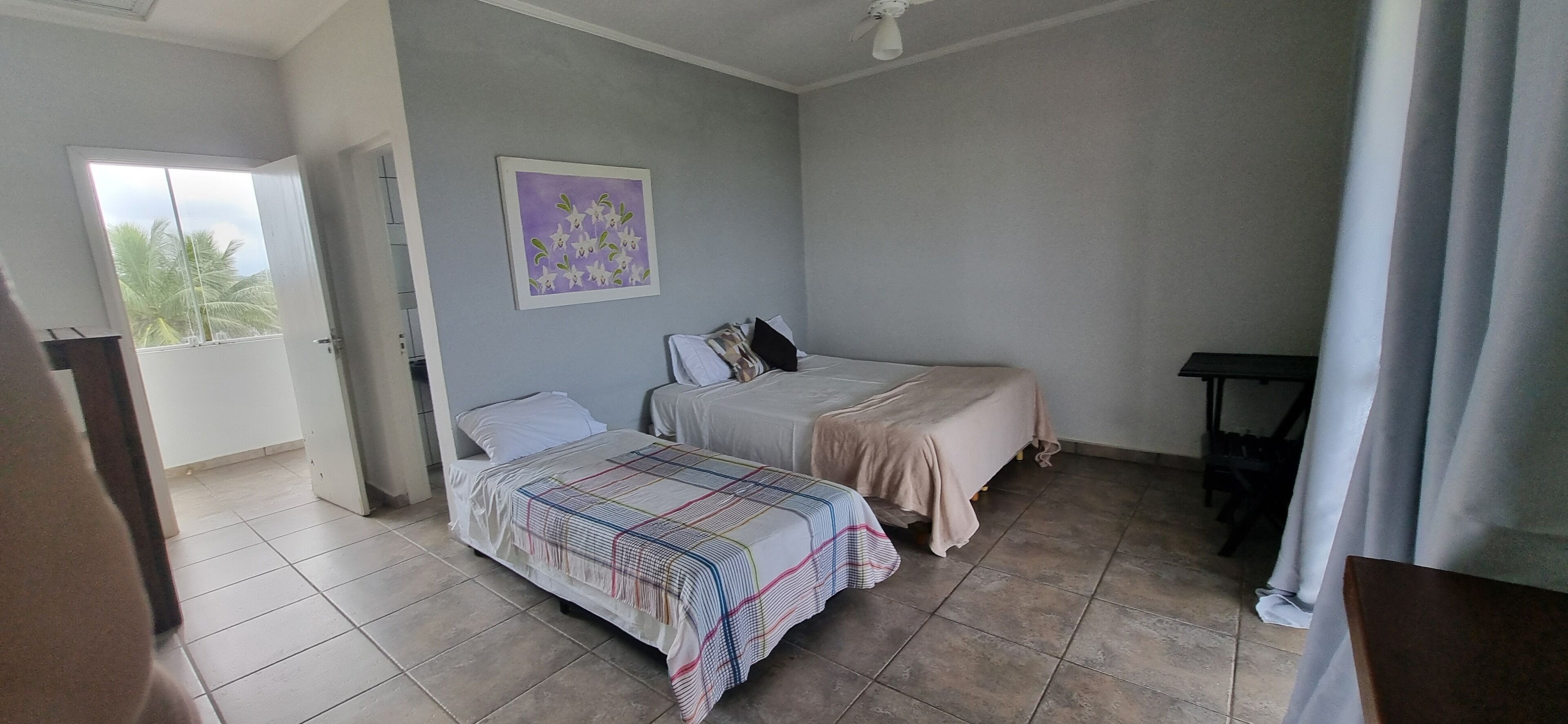 Ein Schlafzimmer mit zwei Betten, einem Deckenventilator und einer Tür, die auf einen Balkon führt.