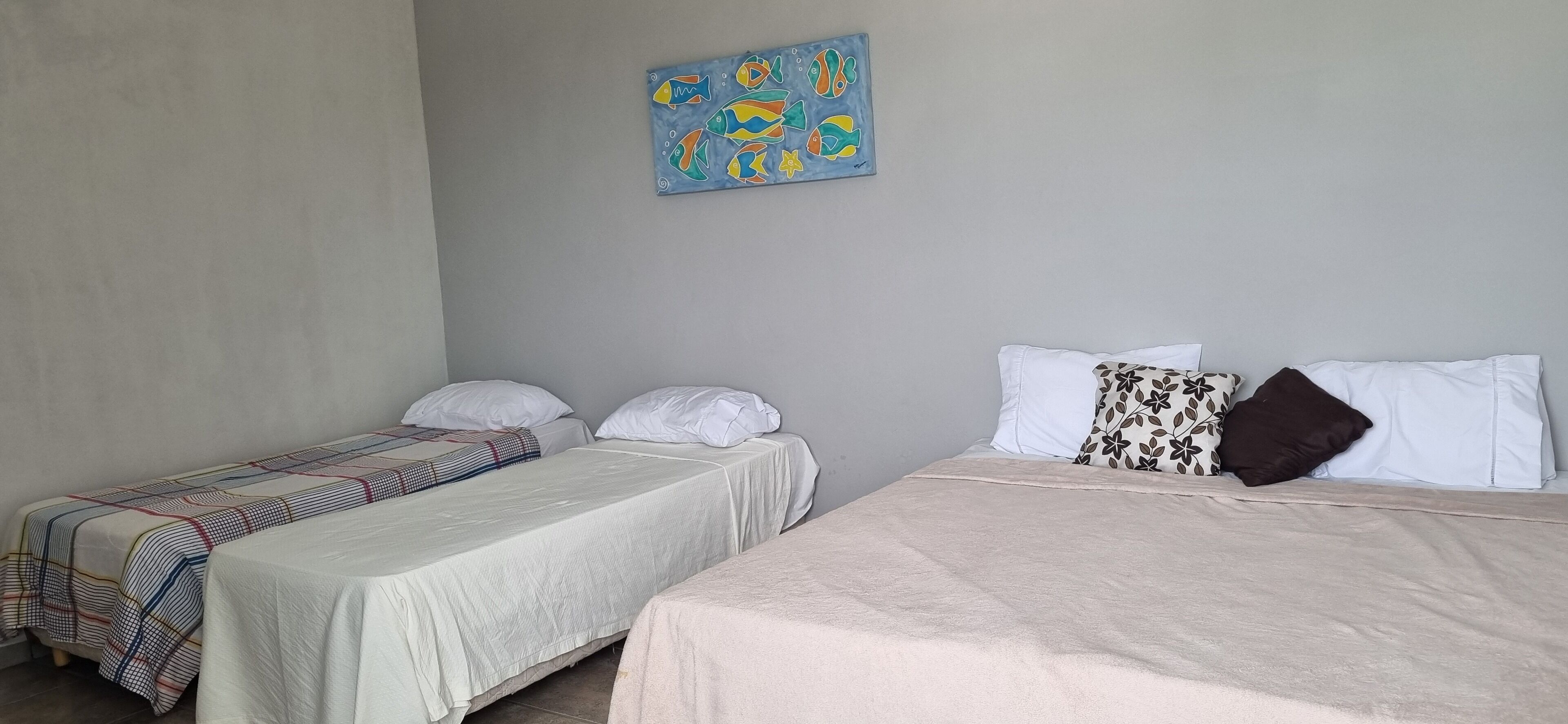 A room with two beds, each with a different patterned bedspread. There is a painting on the wall above the beds.