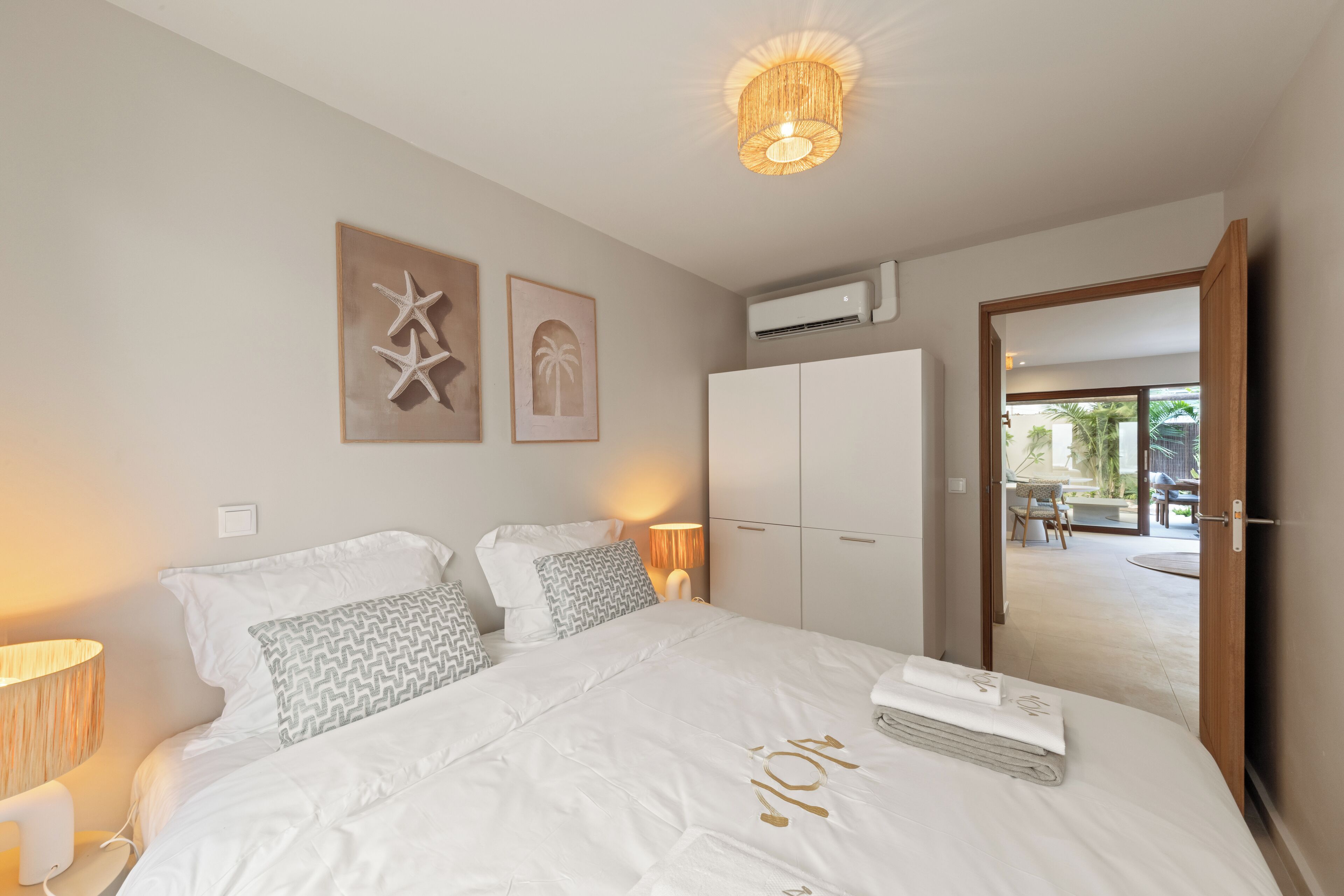 A bedroom with a large bed, a wardrobe, and a door leading to a balcony.