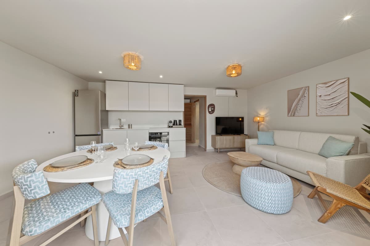 A modern living room with a sofa, ottoman, and dining table with chairs.