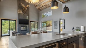 Une cuisine spacieuse dotée d’un grand îlot central, d’appareils électroménagers modernes et d’un plafond au style rustique.