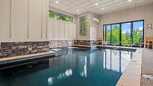 Une piscine avec des murs en pierre et de grandes fenêtres.