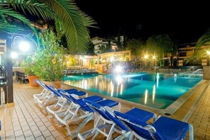 A swimming pool with lounge chairs and a tiled deck area.