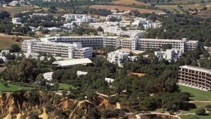 A large hotel complex with multiple buildings, surrounded by greenery and a hilly landscape.