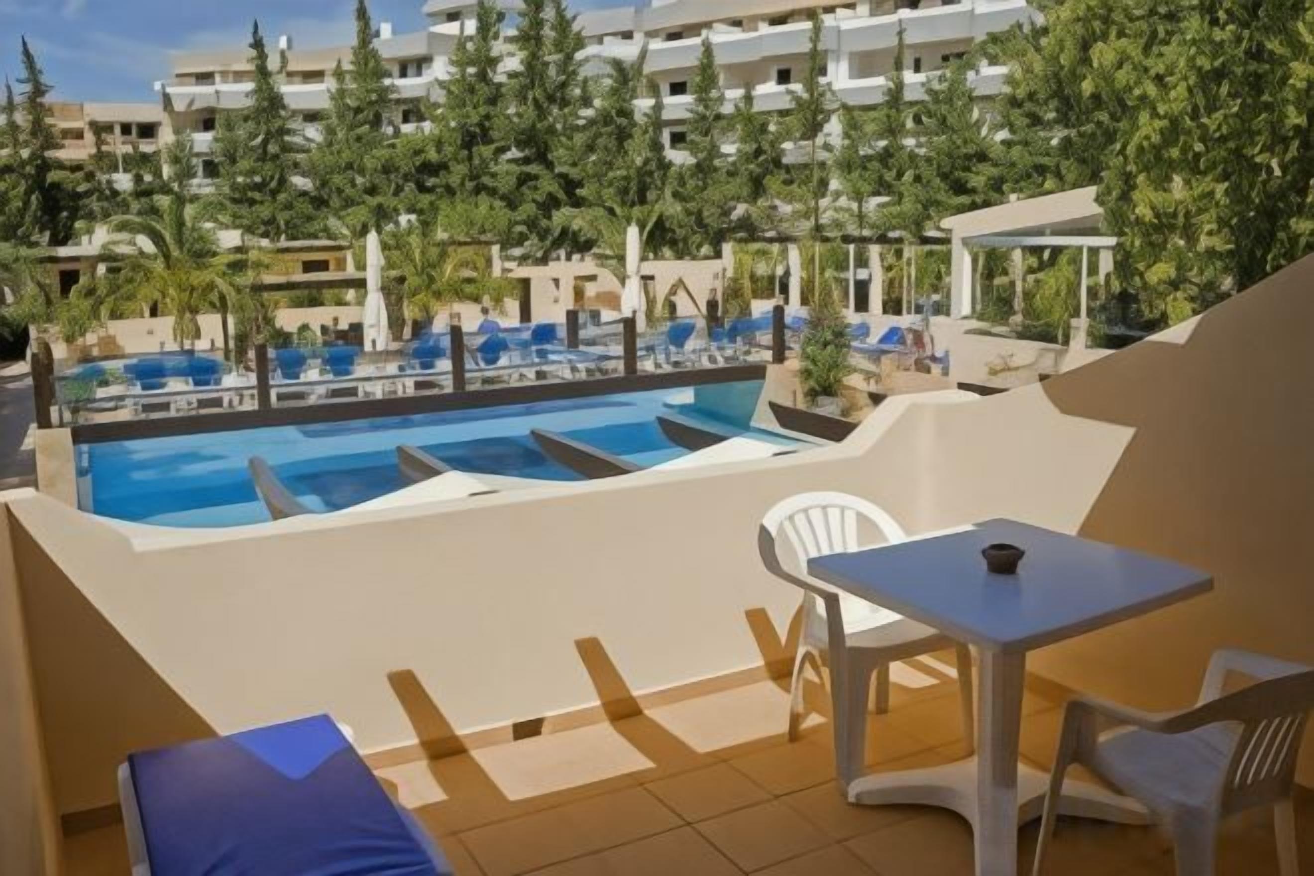 A pool area with multiple swimming pools, lounge chairs, and a table.