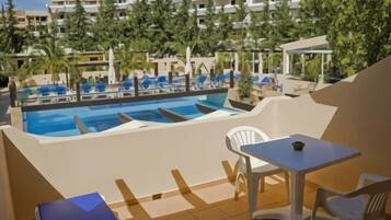 A pool area with multiple swimming pools, lounge chairs, and a table.