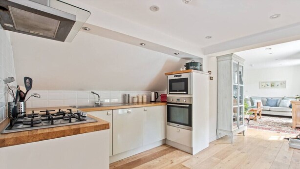 A modern kitchen with a gas stove, oven, and microwave, white cabinetry, and a wooden countertop.