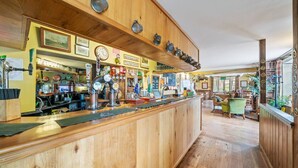 A wooden bar area with a counter, bar stools, and a seating area with a table and chairs.