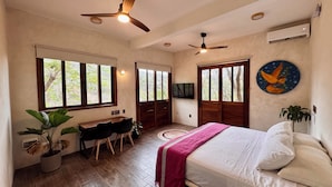 Une chambre spacieuse avec un grand lit, un bureau et deux fenêtres.