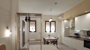 A compact hotel room with a bed, a small dining table with chairs, a kitchenette, and a window with curtains. - A&F House - Ale (Torricella)