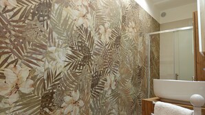 A bathroom with a large floral wallpaper, a bathtub, and a wooden vanity. - A&F House - Ale (Torricella)