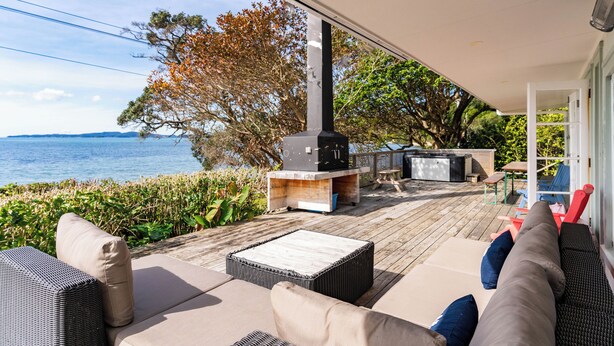 A covered outdoor deck with a view of the sea, a barbecue area, and outdoor seating. - Herons Hideaway - Snells Beach Holiday Home (Snells Beach)