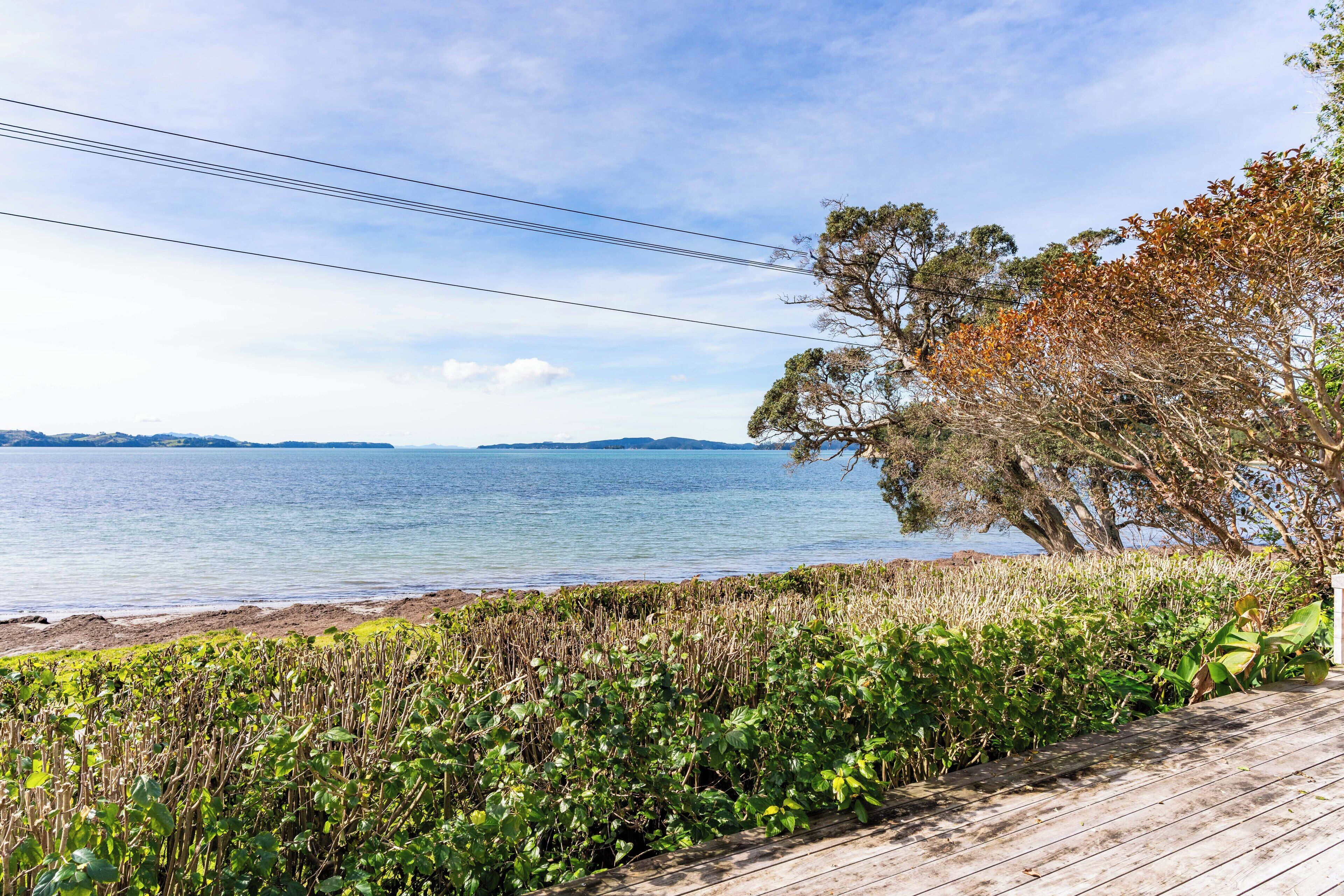 A coastal view with a wooden deck, a body of water, and distant hills.